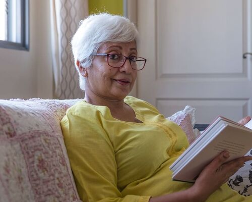 woman-reading-book-while-sitting-on-sofa